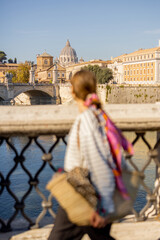 Woman walking on the bridge in Rome on a sunny autumn day. Elegant woman wearing stripped blouse...