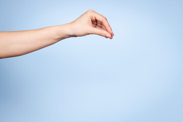 Woman hand gesture. Female hand pose like holding or picking something isolated on light blue...