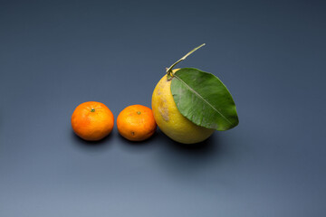 yellow lemon on gray background, composition of lemons and green leaves.