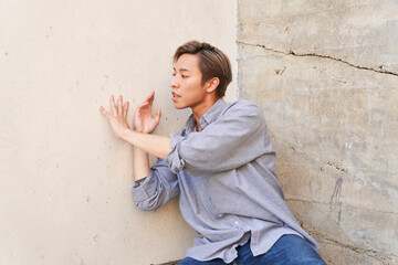 Man dancing leaning by textured concrete wall