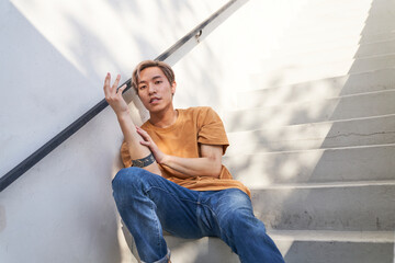 Male dancer sitting on stairs with hand touching arm