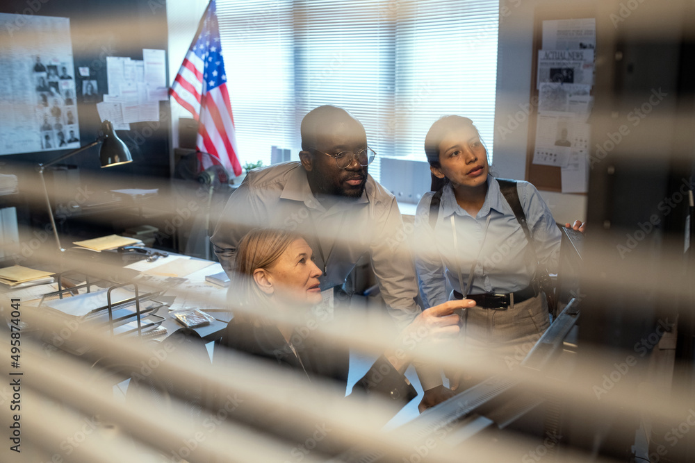 Poster group of fbi agents in formalwear discussing behavior of criminal while watching record from securit