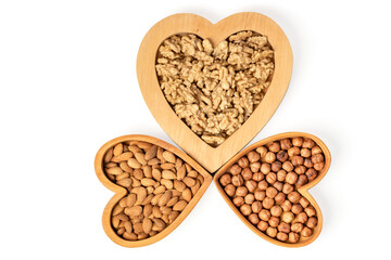Variety of nuts in wooden cups in the shape of a heart isolated on a white background.