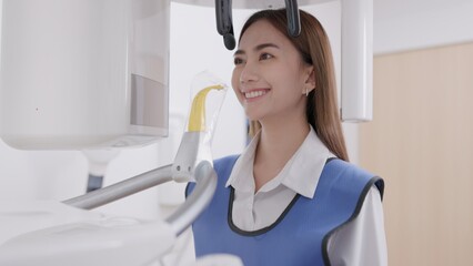 On a panoramic x-ray machine, the dentist aligns the bite of a woman. In a dental clinic, a woman...