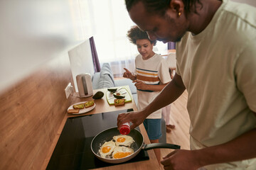 Side view of black family cook breakfast at home