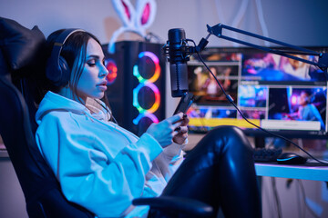 Happy woman putting on headphones and playing computer game. Female gamer in glasses sitting and looking at computer monitor. © Евгений Вершинин