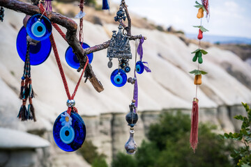 Amulets against evil eye hanging on tree in front of sandy mountain in Cappadocia, Turkey
