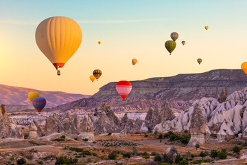 Fototapeta na wymiar Hot air balloons in sunset sky floating over mountains