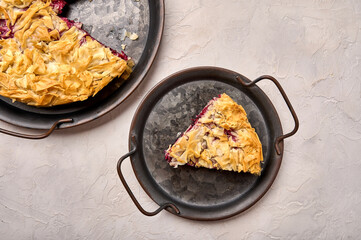 Piece of cherry pie from filo dough on rustic metal tray on light background. Top view