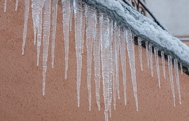 Icicles on the roof. The drain is full of snow and ice. Icicles falling danger concept