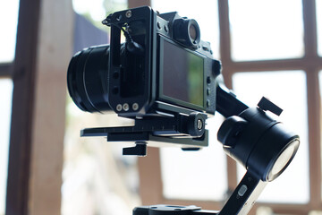 Modern mirrorless camera on 3-axis gimbal stabilizer with recording cable attached to camera and stabilizer