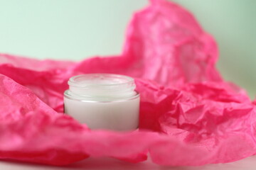 Green cream in crystal jar on pink paper background