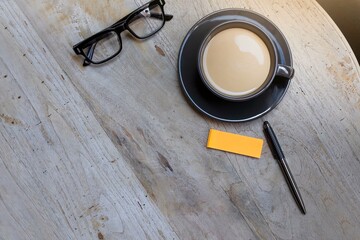 The concept of working from home and paid time off with a cup of coffee, pen, and eyeglasses on the wooden table
