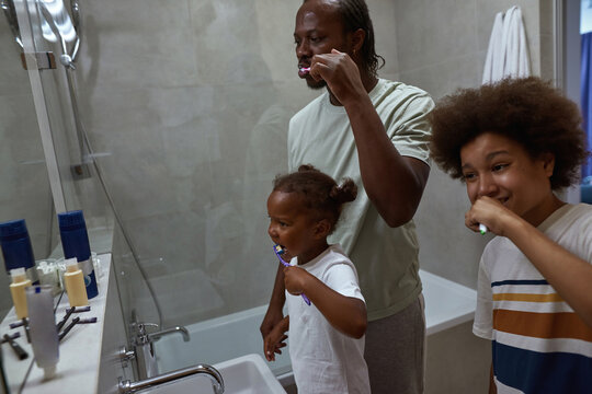 Black Family Brushing Teeth In Bathroom In Morning