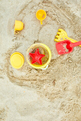 Fototapeta na wymiar Top view, flat lay of scattered plastic beach toys on sand background, family summer vacation, Background with empty space for text
