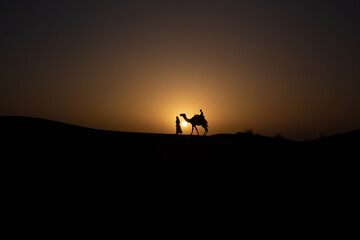 Fototapeta na wymiar silhouette of a person and camel on a sunset