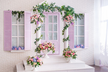 facade of a white and lilac building with a porch decorated with flowers. Photo zone in the photo...