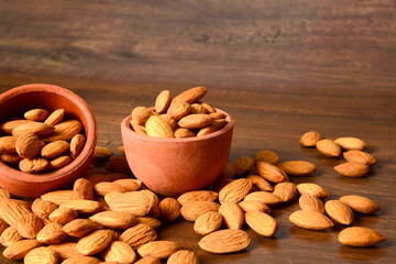 Fresh almonds in the wooden bowl, Organic almonds, almonds border white background, Almond nuts on a dark wooden background. Healthy snacks. Top view. Free space for text.