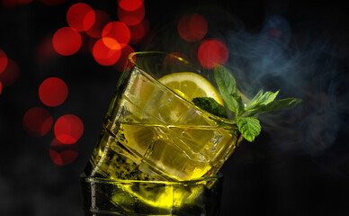 Cocktail with ice, fresh mint and a fresh slice of lemon on a dark background. Cocktails.