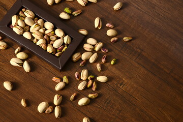 Obraz na płótnie Canvas Fresh almonds in the wooden bowl, Organic almonds, almonds border white background, Almond nuts on a dark wooden background. Healthy snacks. Top view. Free space for text.