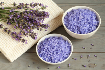 Obraz na płótnie Canvas Sea salt with lavender in a white bowls, and lavender flowers on a linen towels are located on a gray wooden table. Closeup.
