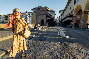 Vrouw lopen op de beroemde oude brug, genaamd Ponte Vecchio, in Florence. Concept van reizende Italiaanse bezienswaardigheden. Stijlvolle vrouw met kleurrijke sjaal en zonnebril. Weids uitzicht bij zonsopgang