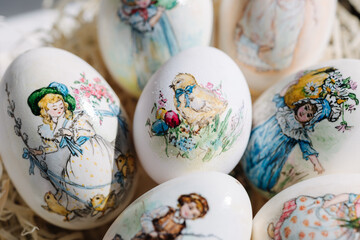 Close-up of different drawings on goose eggs for Easter festival. Eggs on hay. Hand made print. Spring hollidays. Easter concept