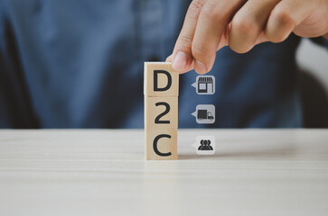 Hand put wooden cubes with Direct to Consumer D2C and icon on table and copy space.Business...