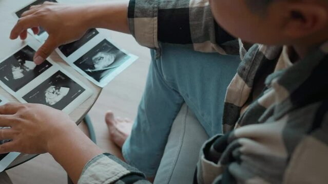 Young father holding ultrasound photo of newborn baby, maternity and family concept