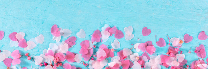 Fototapeta na wymiar Valentine day or wedding panorama with pink hearts and flowers confetti, a flat lay panoramic banner on a blue background with a place for text