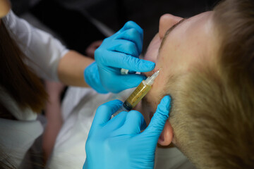 Injection at spa salon. Doctor hands in gloves. Closeup. Pretty male patient. Beauty treatment....