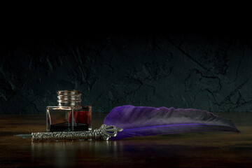 A quill pen with an old inkwell, side view on a black background with a place for text