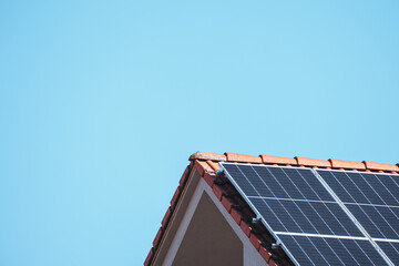Solar photovoltaic panels on a house roof for renewable energy with blue sky