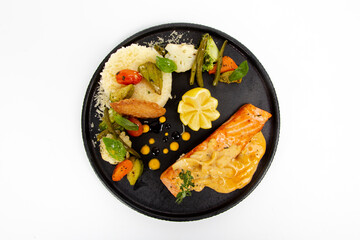 Grilled Salmon with sauteed vegetables and rice cream sauce on black plate