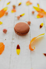 Brown macarons on white background with plant leaves and flowers