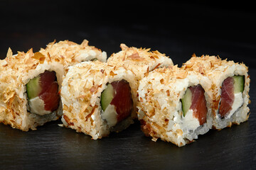 Traditional delicious fresh sushi roll set on a black background. Sushi roll with rice, cream cheese, avocado, salmon, sesame. Philadelphia. Sushi menu. Japanese kitchen, restaurant.