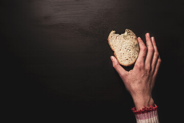 Poverty and hunger - skinny dirty child’s hand reaching for a slice of stale bread
