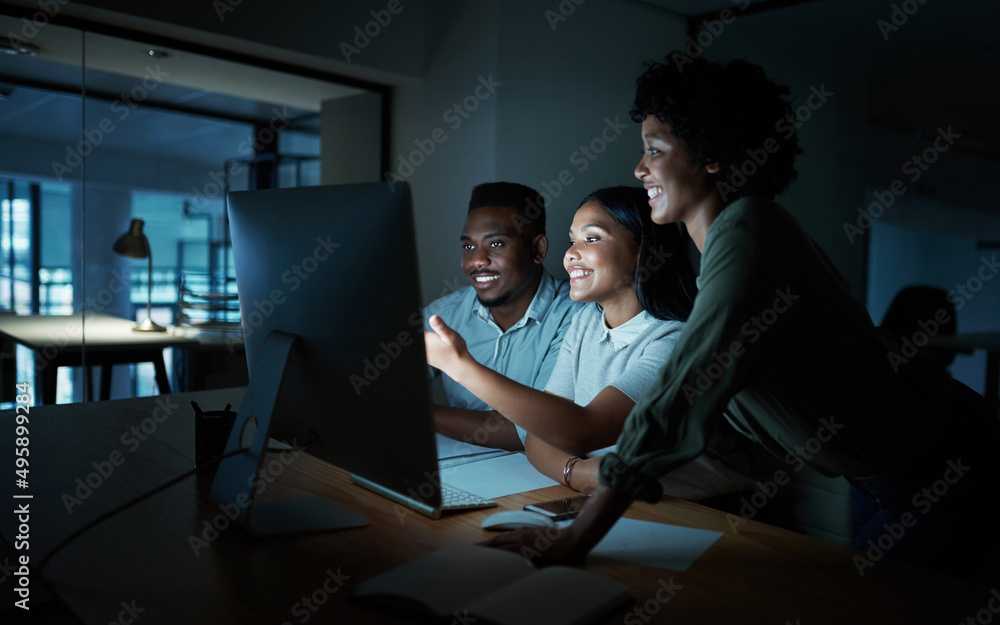 Poster Those who keep at it hold the keys to success. Shot of a group of young businesspeople using a computer together during a late night at work.
