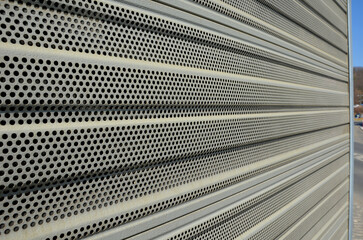noise barrier made of metal perforated sheet metal slats. gray and silver protective fencing...