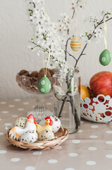 Flowering branches in a jar with water, colorful Easter eggs as decor, vases with apples and walnuts.
