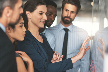 Everyone is in on the plan. Shot of a group of businesspeople looking over plans on a whiteboard.
