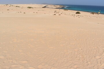 Fototapeta na wymiar Dunes, a road, and the sea in the coast of Fuerteventura