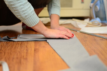 Top view of tailor hands working with scissor and suit textile cloth. Brown suit fabric made of natural wool
