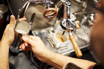 person forming milk at an espresso machine