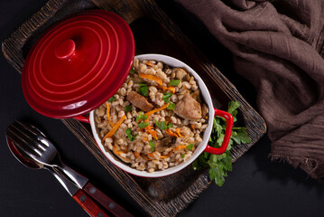 Easy bulgur pilaf (pilavi) with tomatoes in a ceramic bowl on a dark background close-up.