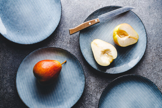 Blue food ceramic set with plates and pears over grey textured background. Minimalist style, top view.