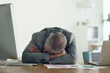 So many deadlines, so little time. Shot of an exhausted businessman resting on his arms at his desk.