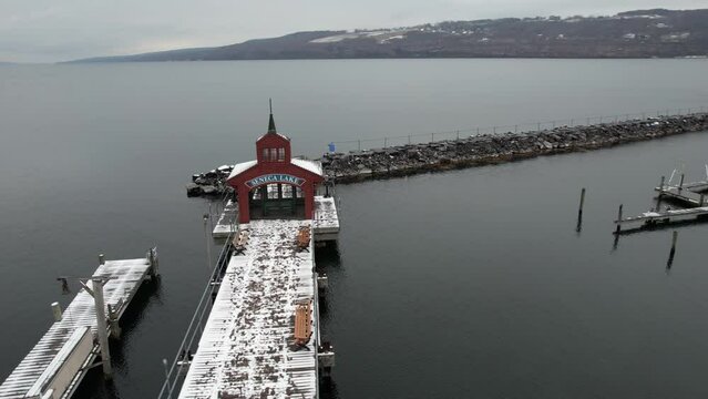 Seneca Lake boat house, harbor and breakwater on cold winter day, drone aerial view of snow capped pier by Watkins Glen village NY USA