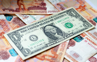 A banknote with a face value of 1 dollar lies on Russian money. The concept of finance, investment, savings and cash.