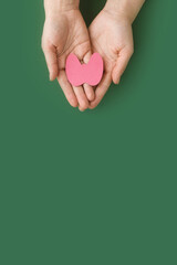 World Thyroid Day. Adult hands holding paper form of thyroid gland on green background. Problems...